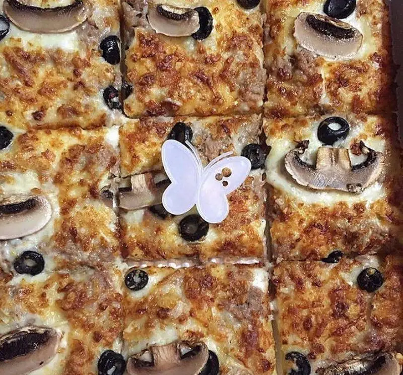 پیتزا پرپروک با تاپینگ‌های خوشمزه شامل گوشت چرخکرده، قارچ، زیتون سیاه و پنیر طلایی. این پیتزا اشتهاآور آماده سرو است.