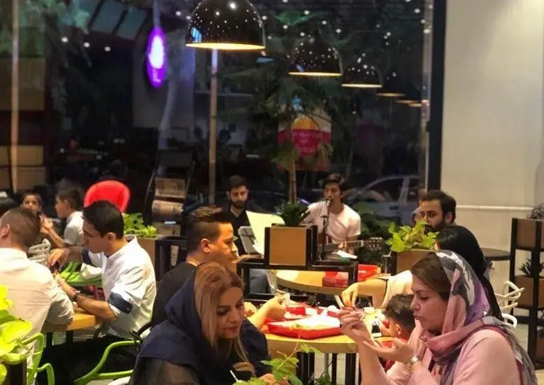 تصویری از محیط دلنشین پیتزا پرپروک با مشتریانی که در حال صرف غذا و لذت بردن از موسیقی زنده هستند. مناسب برای خانواده و دوستان.