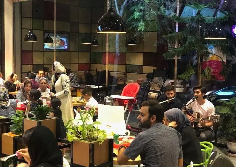 فضای گرم و دلنشین رستوران پیتزا پرپروک با حضور مشتریان و اجرای زنده موسیقی، محیطی عالی برای یک دورهمی خانوادگی.