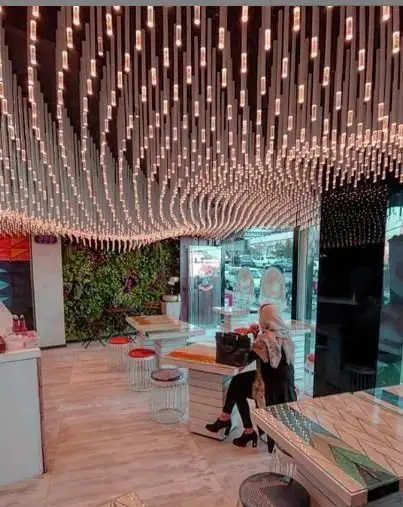 فضای داخلی مدرن و شیک رستوران برگر قلب سفید با سقف نورپردازی خاص، دیوار سبز و میزهای طراحی شده برای تجربه غذایی دلپذیر.