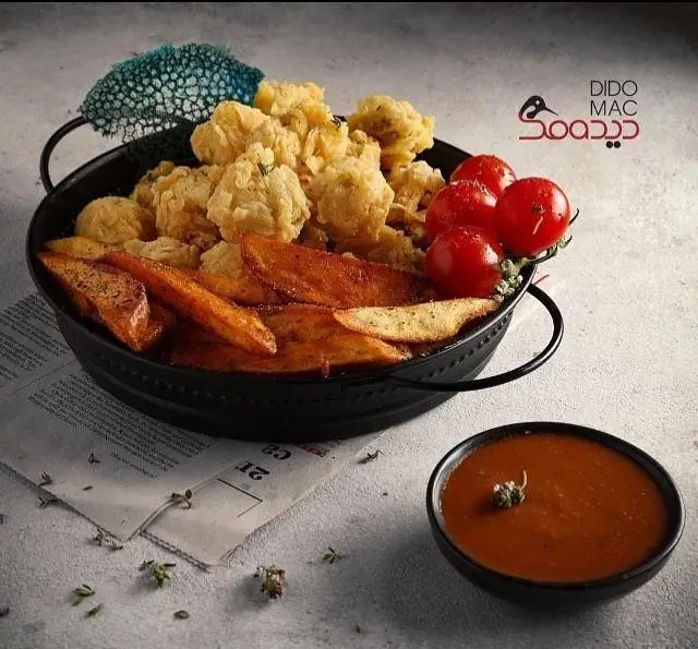 کاسه‌ای جذاب از سیب زمینی سرخ شده و سوخاری طلایی کافه فست فود دیدومک، با گوجه گیلاسی و سس ویژه. غذای دیدومک.