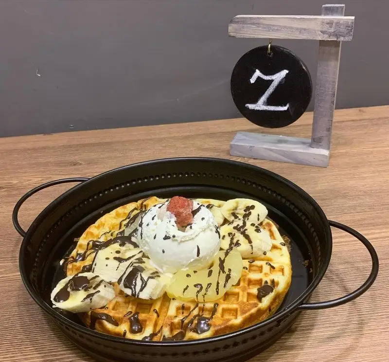 دسر وافل دلپذیر کافه و فست فود دیدومک با بستنی، موز تازه، میوه‌های خرد شده و سس شکلات، تجربه‌ای شیرین و لذت‌بخش.