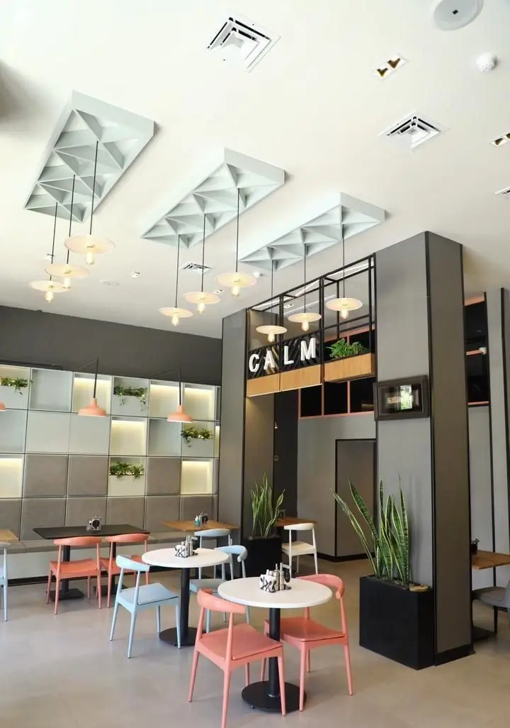 فضای داخلی کافه و فست فود دیدومک با دکوراسیون مدرن، صندلی‌های رنگی، نورپردازی خاص و گیاهان طبیعی، محیطی آرامش‌بخش را فراهم کرده است.