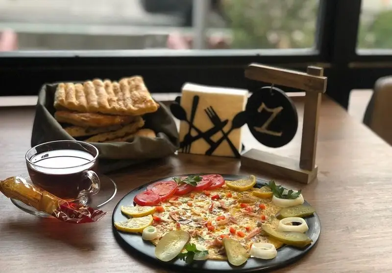 میز صبحانه جذاب کافه و فست فود دیدومک: املت مخصوص، نان گرم، چای و مخلفات در محیطی دنج و مناسب برای شروع یک روز عالی.