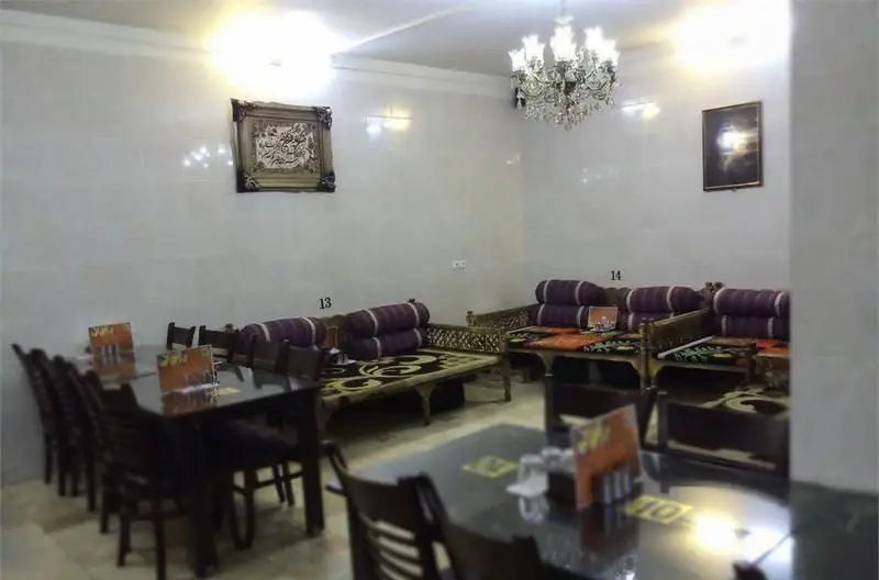 نمایی از فضای داخلی رستوران ایرانی بزرگ خاندان، شامل میز و صندلی و تخت‌های سنتی با دکوراسیون شیک و نورپردازی مناسب.