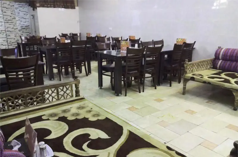 تصویری از محیط دلنشین و سنتی رستوران ایرانی بزرگ خاندان، با چیدمان میز و صندلی‌های چوبی و تخت سنتی برای پذیرایی از مهمانان.