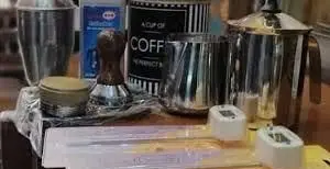 مجموعه‌ای از ابزار و تجهیزات حرفه‌ای تهیه قهوه برای کافه فنجون: تمپر، پیچر، شیکر، قهوه ساز و دماسنج شیر.