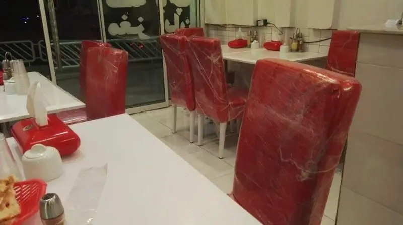 فضای داخلی دنج و تمیز طباخی کیا با میزهای سفید و صندلی‌های قرمز روکش‌دار آماده ارائه بهترین کله‌پاچه به مشتریان.