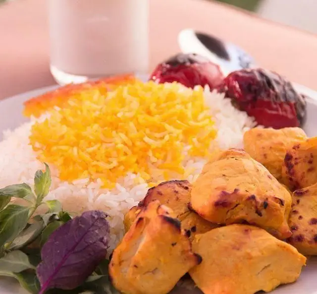 غذای محبوب جوجه کباب زعفرانی همراه با برنج ایرانی، گوجه کبابی و سبزی تازه، انتخابی ایده‌آل در رستوران چنجه.