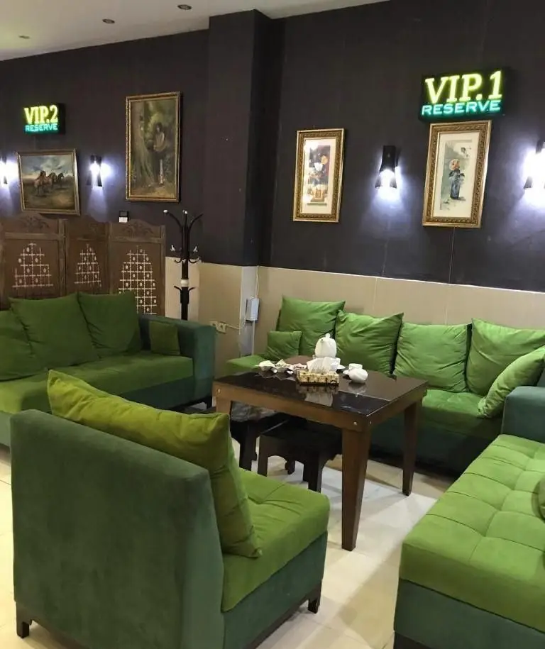 فضای داخلی رستوران ایرانی نارنج با مبلمان سبز راحت، دیوارهای تیره، تابلوهای هنری و علائم VIP برای رزرو. محیطی دلنشین و آرام برای مشتریان.