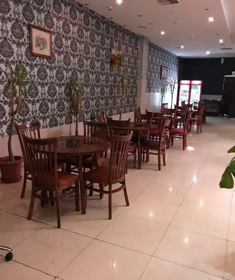 فضای داخلی رستوران ایرانی نارنج با میز و صندلی‌های چوبی، دیوارهای طرح‌دار و گیاهان سبز، محیطی دلنشین برای صرف غذا.