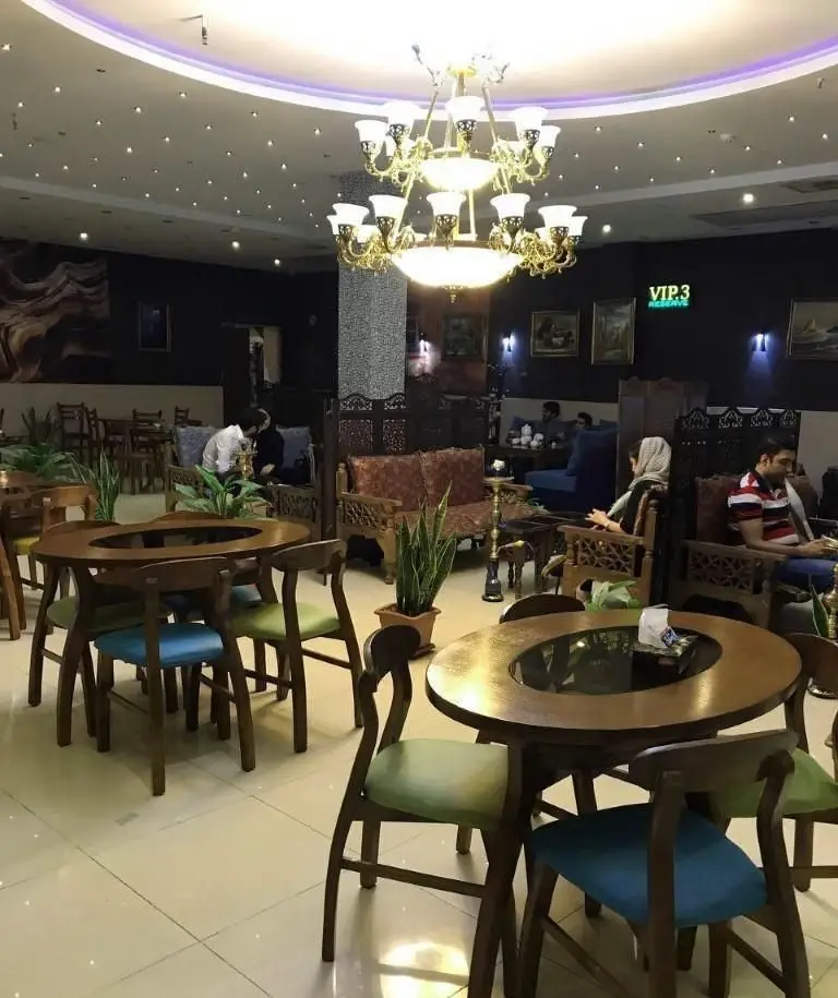 فضای داخلی دنج و دلنشین رستوران ایرانی نارنج با دکوراسیون سنتی و میزهای چوبی شیک، مناسب برای دورهمی و سرو غذا و قلیان.