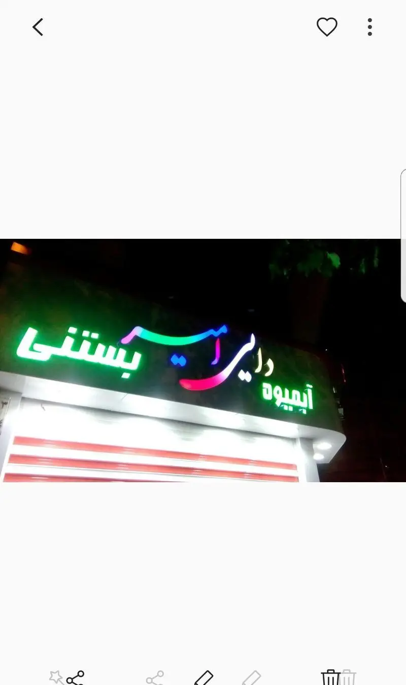 تابلوی نئون روشن و رنگی فروشگاه آبمیوه و بستنی دایی امیر در شب، با نام برند 'آبمیوه، بستنی دایی امیر' به خط فارسی و جذاب.