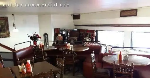 فضای داخلی فست فود پیتزا پیشخوان با میز و صندلی‌های چوبی و مبلمان راحتی. دکوراسیون دلنشین، نور طبیعی، محیطی ایده‌آل برای صرف پیتزا و فست فود.