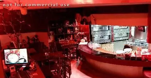 تصویر داخلی فست فود پیتزا با پیشخوان مدرن سفارش، آشپزخانه مجهز با فر پیتزا و فضای غذاخوری شیک برای تجربه دلپذیر مشتریان.