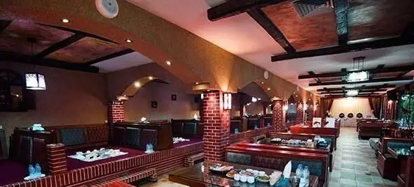 دکوراسیون داخلی و فضای دلنشین کافی شاپ ترمه با نشیمن‌های سنتی، میز و صندلی‌های مدرن، آجرکاری و نورپردازی گرم آماده پذیرایی.