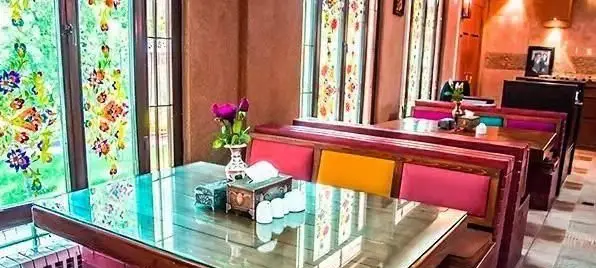 کافی شاپ ترمه: دکوراسیون داخلی سنتی با پنجره‌های طرح‌دار رنگی، میزهای شیشه‌ای و نیمکت‌های راحت. فضایی آرام و دلپذیر برای پذیرایی.