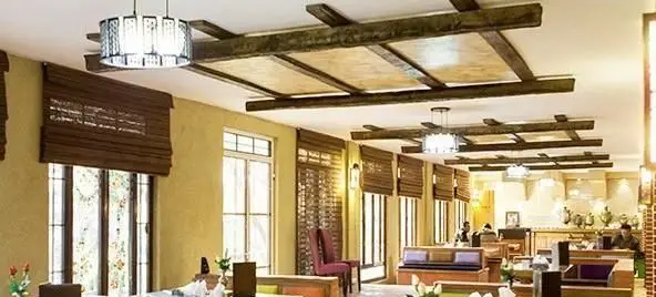 دکوراسیون داخلی دنج و سنتی کافی شاپ ترمه با سقف چوبی، پنجره‌های بلند و نورپردازی زیبا، فضایی آرام برای مشتریان.