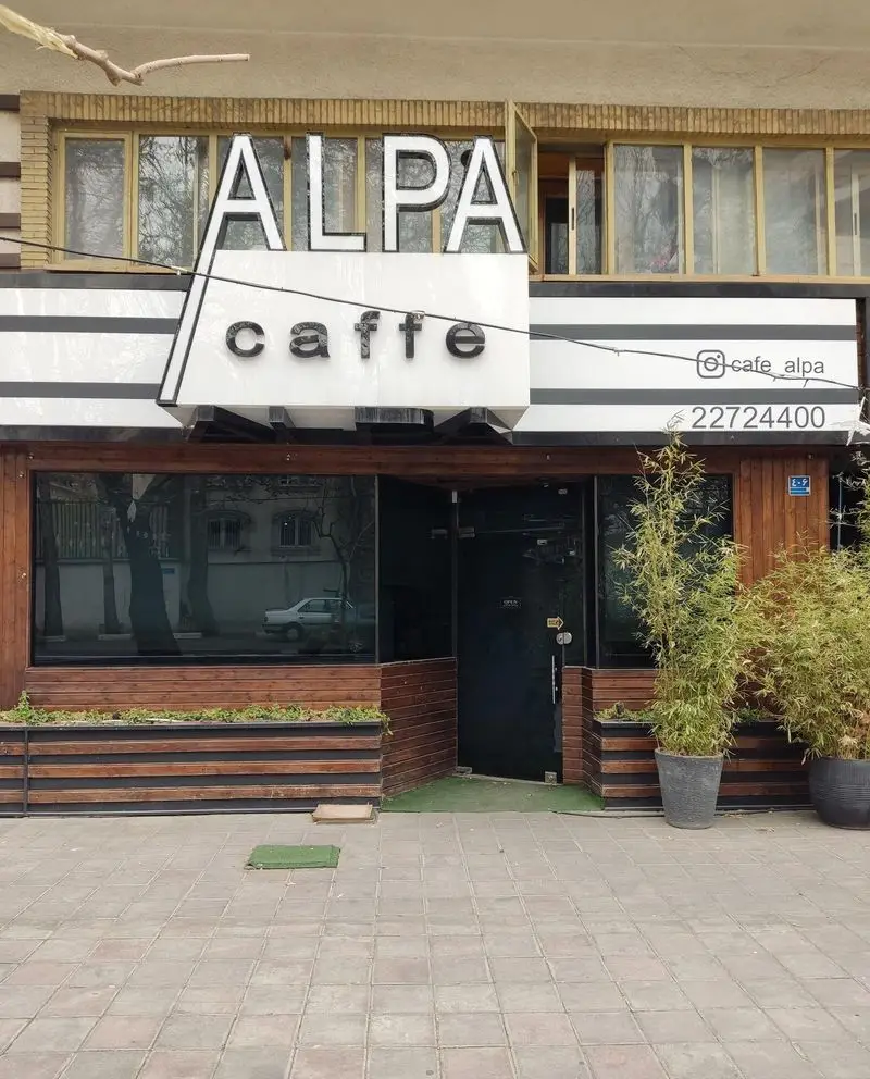 نمای بیرونی کافه رستوران آلپا با تابلوی ALPA caffe، شامل آدرس اینستاگرام cafe_alpa@ و شماره تماس 22724400 برای مشتریان.