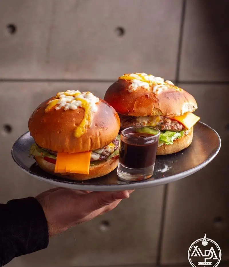 همبرگرهای ویژه و خوشمزه کافه رستوران آلپا، با پنیر فراوان، نان تازه و سس مخصوص، آماده سرو و ارائه تجربه‌ای لذیذ.