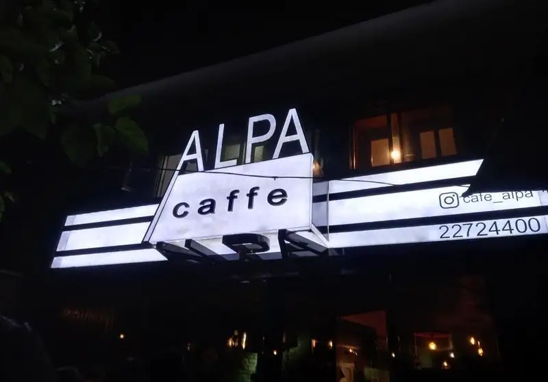 تصویری در شب از تابلوی روشن کافه رستوران آلپا شامل نام ALPA caffe، آدرس اینستاگرام cafe_alpa و شماره تماس 22724400.