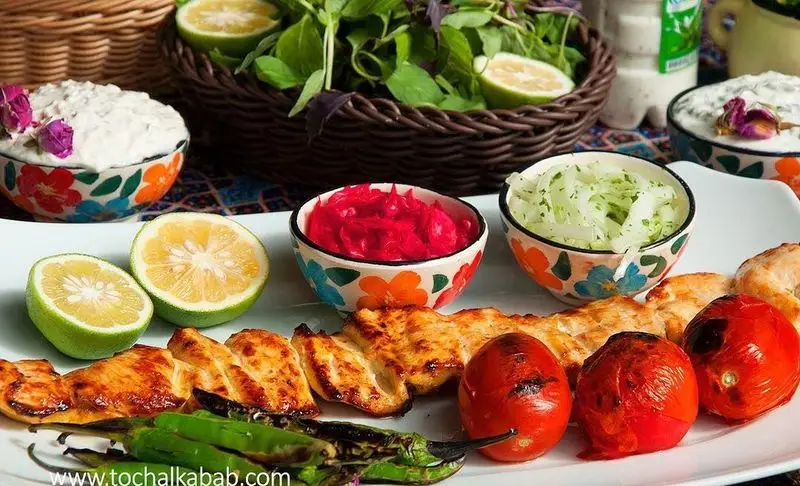 جوجه کباب لذیذ کباب سرای توچال با گوجه کبابی، فلفل و دورچین تازه: سبزی، ماست و خیار و لیمو. غذای اصیل ایرانی.