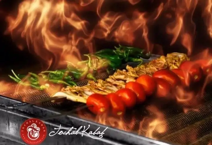 کباب‌های خوشمزه (فلفل، گوجه، مرغ) روی آتش داغ کباب‌پز، آماده سرو در کباب سرای توچال. طعم اصیل کباب ایرانی.