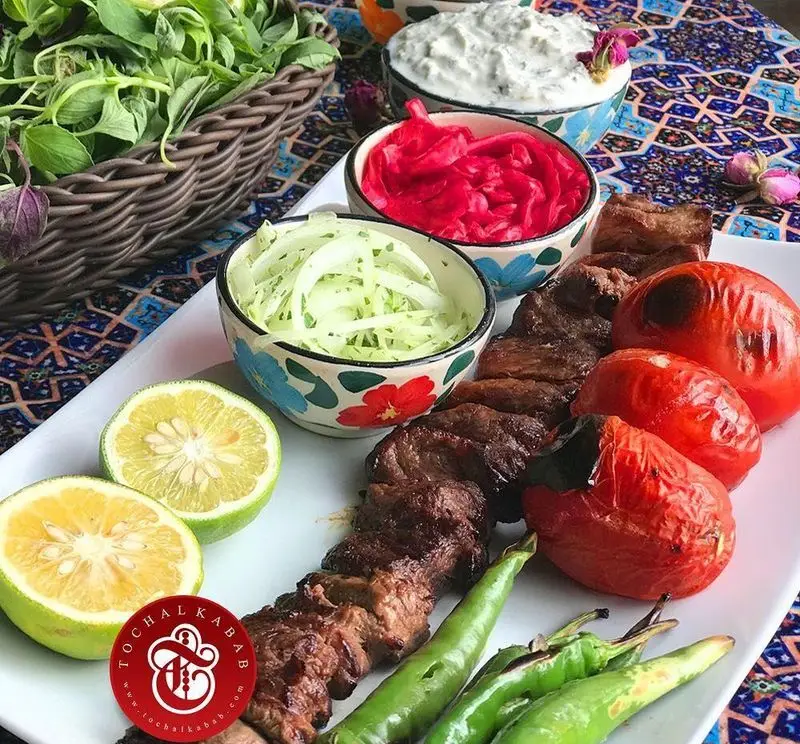 کباب سرای توچال: کباب گوشت لذیذ با گوجه، فلفل کبابی، سبزی خوردن تازه، پیاز، لیمو، ماست و خیار و ترشی. تجربه غذای ایرانی اصیل.