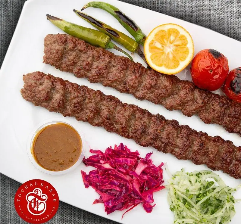 کباب کوبیده اصیل ایرانی با فلفل، گوجه و لیمو گریل شده، سس مخصوص، کلم قرمز و پیازجعفری در کباب سرای توچال.