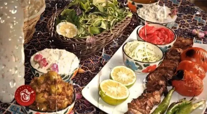 میز غذای کامل ایرانی از کباب سرای توچال شامل کباب، گوجه، سبزی، ماست، ترشی و زیتون پرورده. تجربه طعم اصیل ایرانی.
