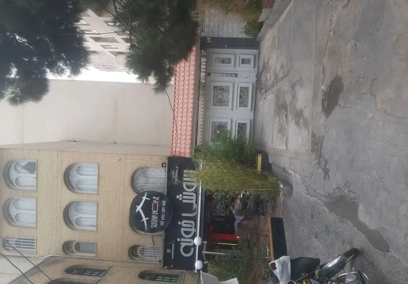 نمای بیرونی رستوران سوشی خونه، تابلوی «SUSHIKHOONE All you can eat» در روز، ساختمان با معماری خاص و پنجره‌های قوسی در خیابان