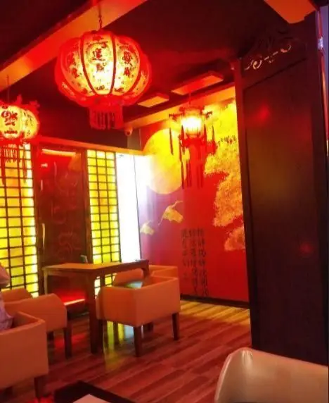 دکوراسیون داخلی جذاب رستوران سوشی خونه با فانوس‌های قرمز چینی، دیوارنگاره‌های شرقی و چیدمان گرم و دوستانه میز و صندلی‌ها.