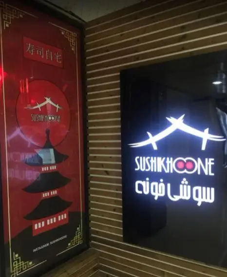 نمای بیرونی رستوران سوشی خونه: تابلوی درخشان با لوگو و نام SUSHIKHOONE و سوشی خونه، بنر قرمز با طرح پاگودا و سوشی ژاپنی.