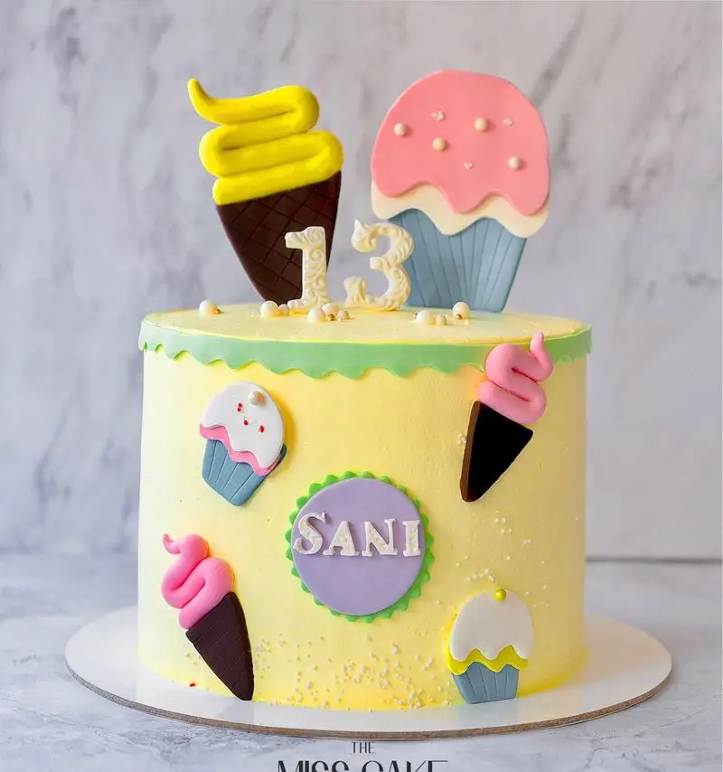 کیک تولد ۱۳ سالگی سفارشی برای "سانی" با تزیینات بستنی، کاپ کیک و رنگ زرد جذاب از میس کیک.