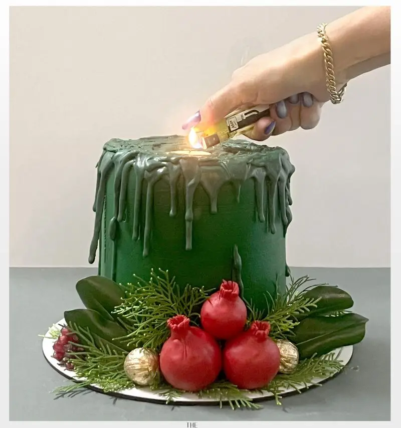 کیک سبز شمعی با دیزاین خاص قطرات تیره، تزئین شده با انار، برگ کاج و مروارید طلایی، ایده عالی برای شب یلدا و کریسمس از میس کیک.