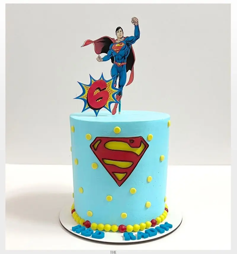 کیک تولد پسرانه با تم سوپرمن و رنگ آبی جذاب، تزیین شده با فیگور سوپرمن و عدد 6، لوگوی سوپرمن. سفارش کیک از میس کیک.