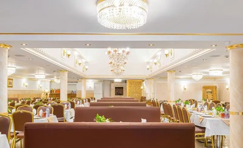 تصویری از سالن غذاخوری بزرگ و لوکس رستوران باباخانی، با میزهای چیده شده برای پذیرایی. دکوراسیون مجلل، لوسترهای کریستالی و ستون‌های طلایی.