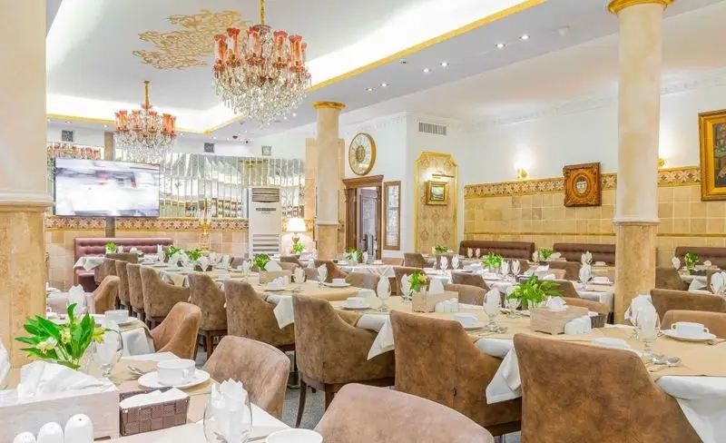 فضای داخلی لوکس و مجلل رستوران باباخانی، با لوسترهای کریستالی، دکوراسیون طلایی و میزهای چیده شده برای پذیرایی.