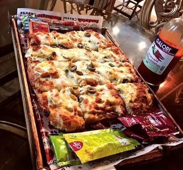 پیتزا مستطیلی خوشمزه با زیتون و پنیر در کافه و رستوران عمارت، همراه با سس تند و کچاپ. غذایی عالی برای ناهار یا شام.