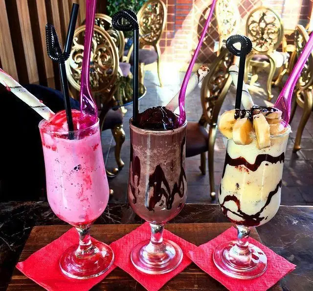 سه میلک شیک محبوب (توت فرنگی، شکلات، موز) با تزیین جذاب در کافه، کافی شاپ و رستوران عمارت. لذت یک نوشیدنی خنک و دلپذیر.