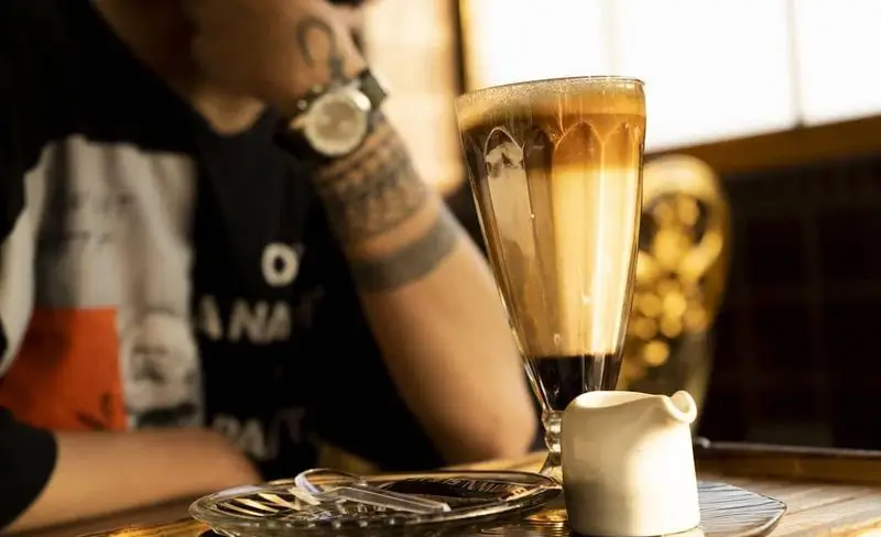 لته چندلایه جذاب در کافه و کافی شاپ عمارت، همراه با مشتری در فضای دنج رستوران؛ تجربه نوشیدنی قهوه عالی.