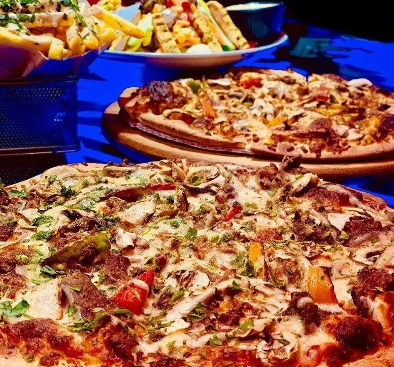 پیتزاهای جذاب و تازه گوشت و قارچ پیتزا شب با سس سفید و سبزیجات، در کنار سیب زمینی سرخ کرده و ساندویچ.