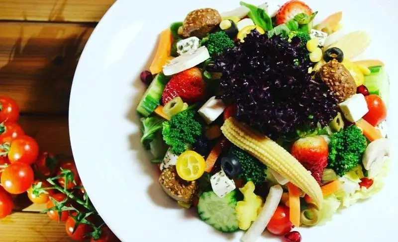 سالاد رنگارنگ و تازه پیتزا شب با انواع سبزیجات، میوه‌ها، پنیر، زیتون و بروکلی، انتخابی سالم و جذاب برای مشتریان.