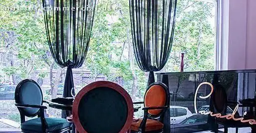 فضای داخلی لوکس کافی شاپ پارادیزو با مبلمان دنج و پنجره‌های بزرگ رو به فضای سبز بیرونی، محیطی آرامش‌بخش و دلنشین.