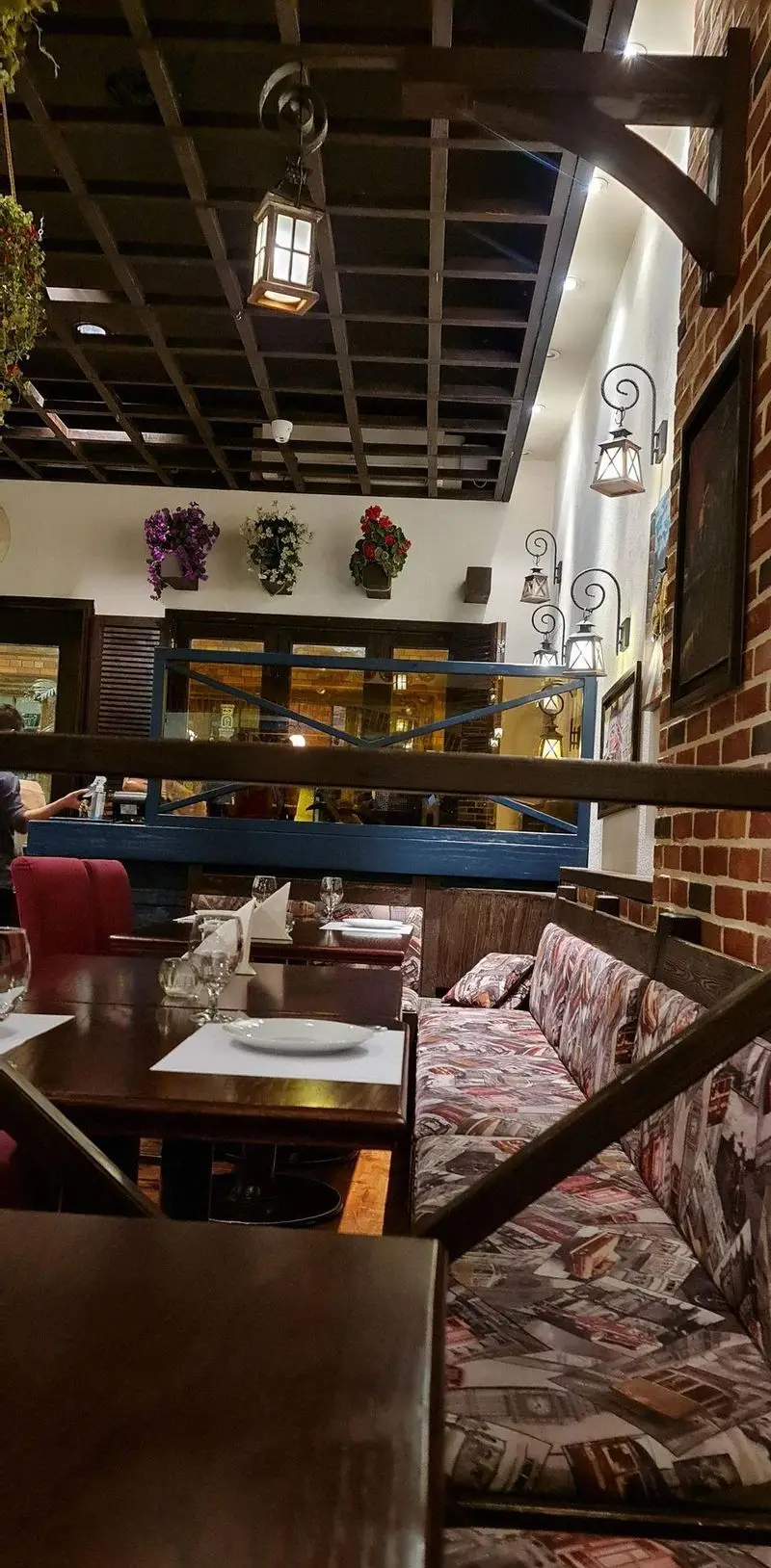 تصویری از فضای داخلی گرم و دلنشین رستوران ایتالیایی پارلا، با سقف چوبی، دیوار آجری، فانوس‌های زیبا و میزهای چوبی آماده سرو غذا.