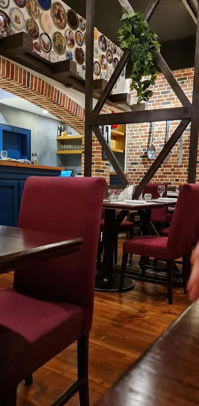 نمای دنج و شیک از دکوراسیون داخلی رستوران ایتالیایی پارلا. فضایی گرم با صندلی‌های قرمز، دیوار آجری و تزئینات بشقاب‌های سنتی.