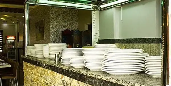 نمای داخلی طباخی کاج سعادت آباد با پیشخوانی پر از بشقاب و کاسه‌های تمیز آماده پذیرایی از مشتریان برای سرو کله پاچه.