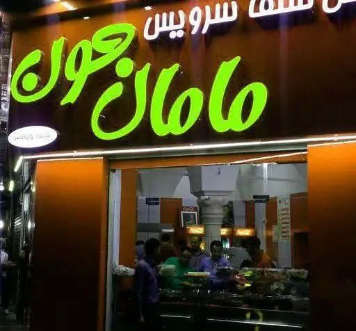 نمای شبانه سوپر گوشت و مرغ مرکزی با تابلوی روشن و مشتریان در داخل. محیطی پرنور و دعوت کننده برای خرید گوشت و مرغ تازه.