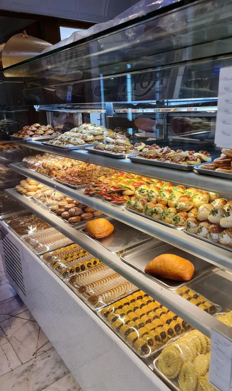 ویترین جذاب شیرینی‌فروشی سوگل با انواع شیرینی‌های تازه، دسرها و نان‌های فانتزی آماده سرو در محیطی دلنشین.