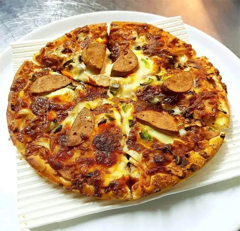 تصویر یک پیتزا سوسیس و سبزیجات تازه فست فود جاسنتو با پنیر آب شده و نان برشته، مناسب برای سفارش آنلاین.